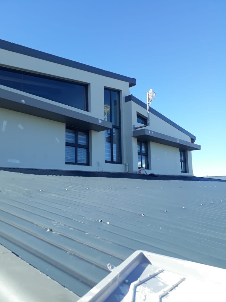 Newly coated grey roof on a modern West Coast home under a blue sky